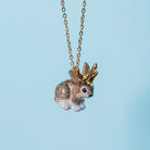 Camp Hollow Gold Jackalope Necklace on a blue background