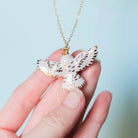Golden Snowy Owl Necklace on a blue background at Addison West