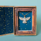 Golden Snowy Owl Necklace gift box on a blue background at Addison West