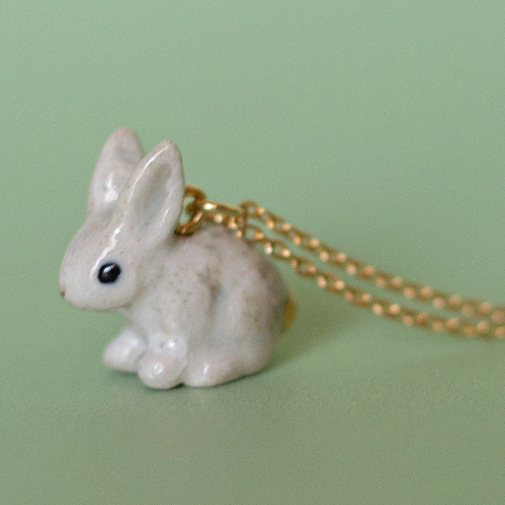 Camp Hollow Porcelain Goldentail Rabbit Necklace on green background.