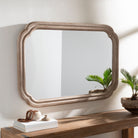 Harlan Accent Mirror on a white wall above a table at Addison West