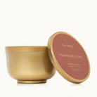 Thymes Pomander Clove Tin Candle 6.5oz on a red background at Addison West