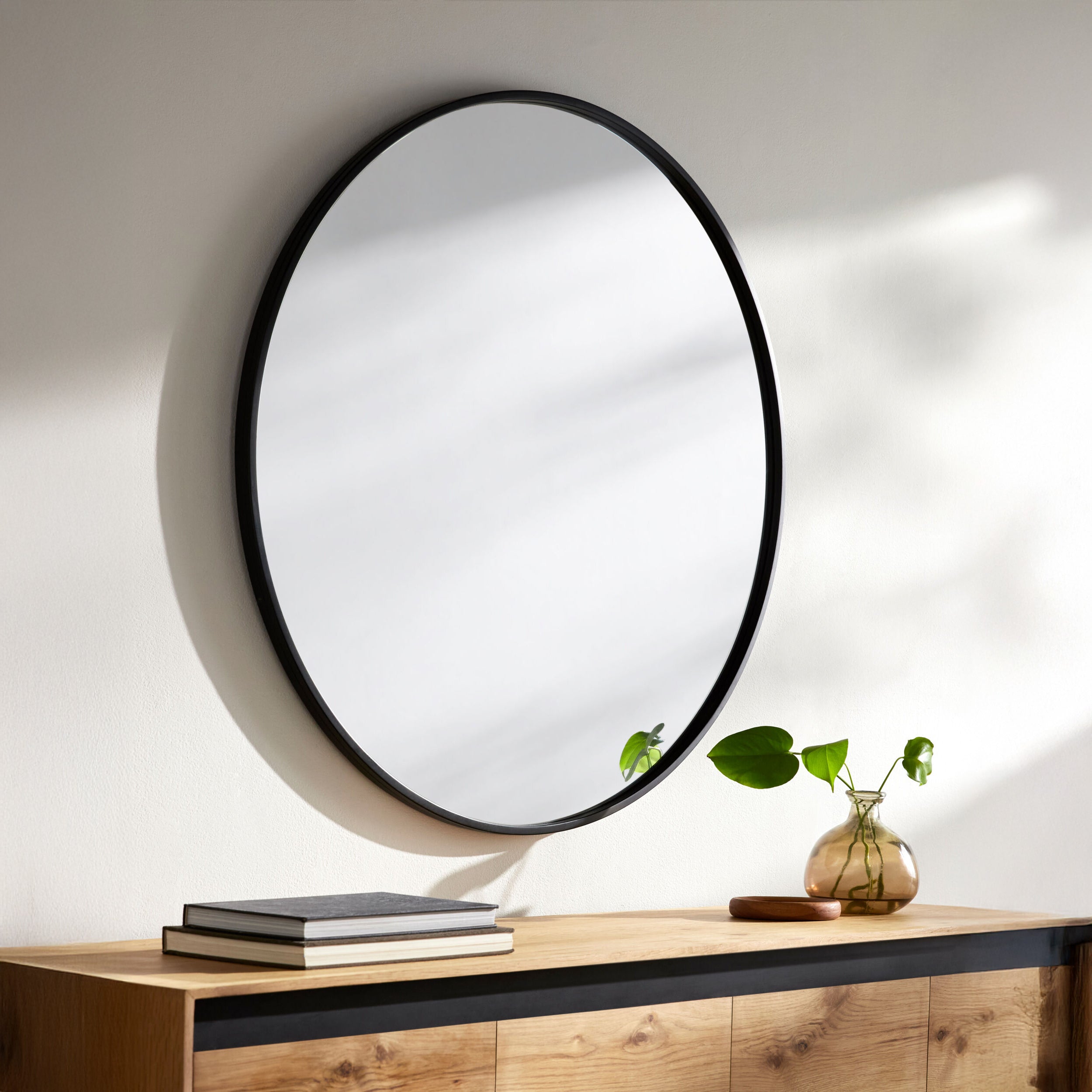 Carmen Accent Mirror on a white wall above a table  at Addison West 
