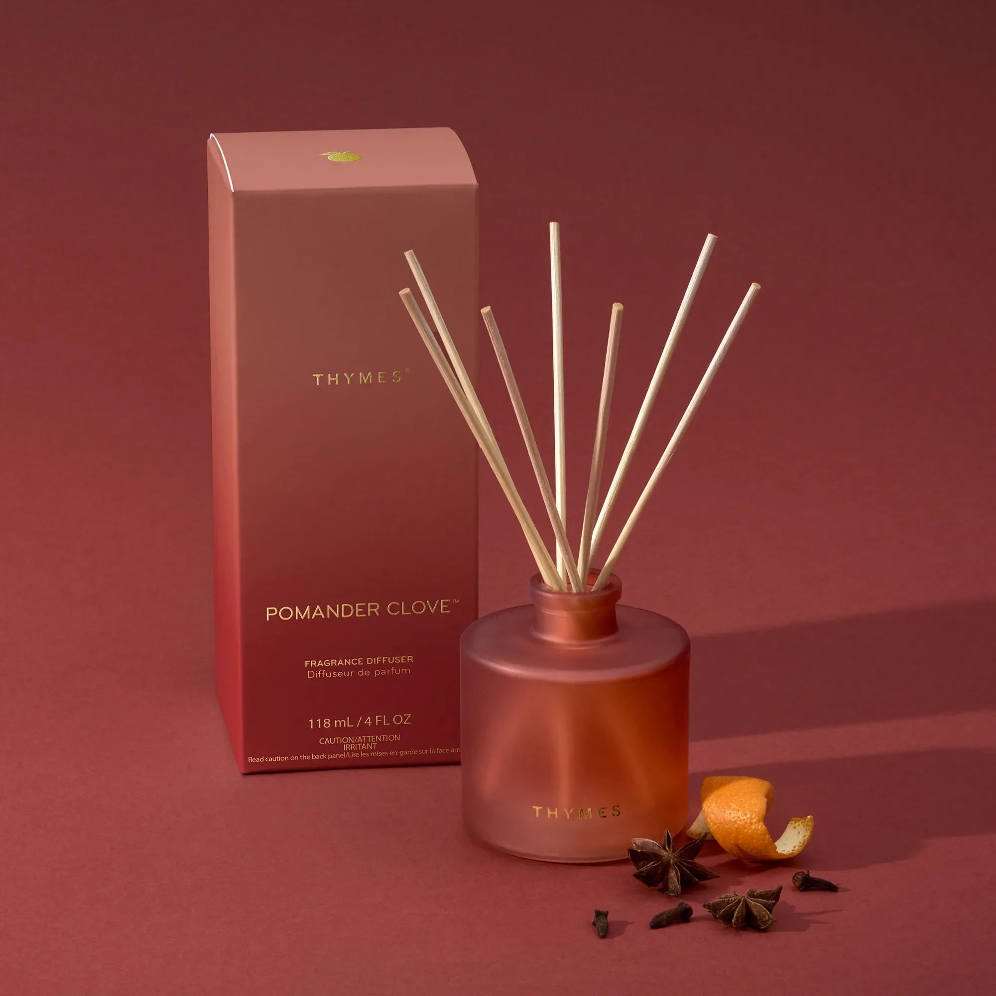 Thymes Pomander Clove Petite Diffuser 4oz on a red background at Addison West