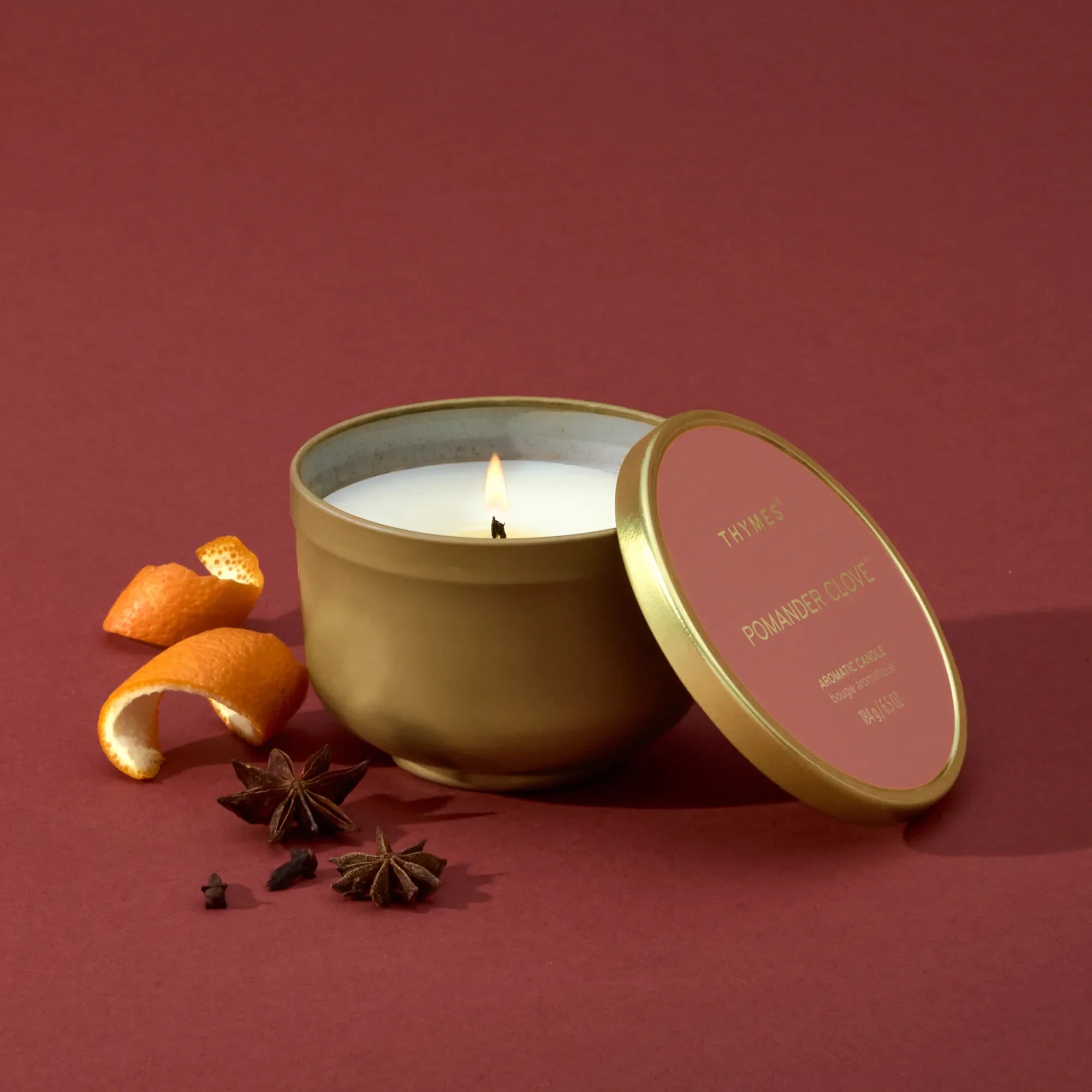 Thymes Pomander Clove Tin Candle 6.5oz on a red background at Addison West