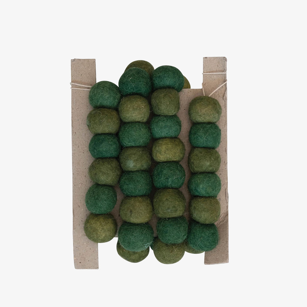 Green felted wool ball garland on a white background
