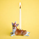 Dog-shaped candle holder with a lit candle on a yellow background
