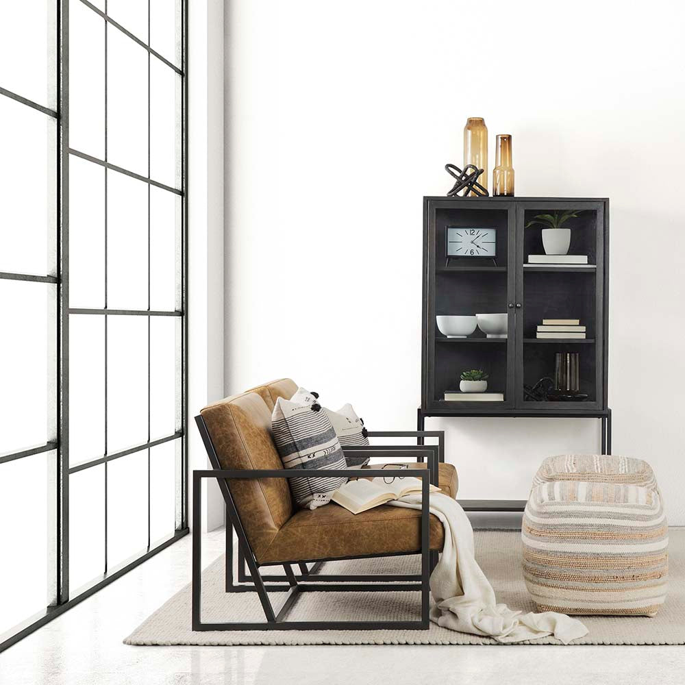 Black display cabinet with glass doors in a room with white walls, two arm chairs and metal frame sliding doors