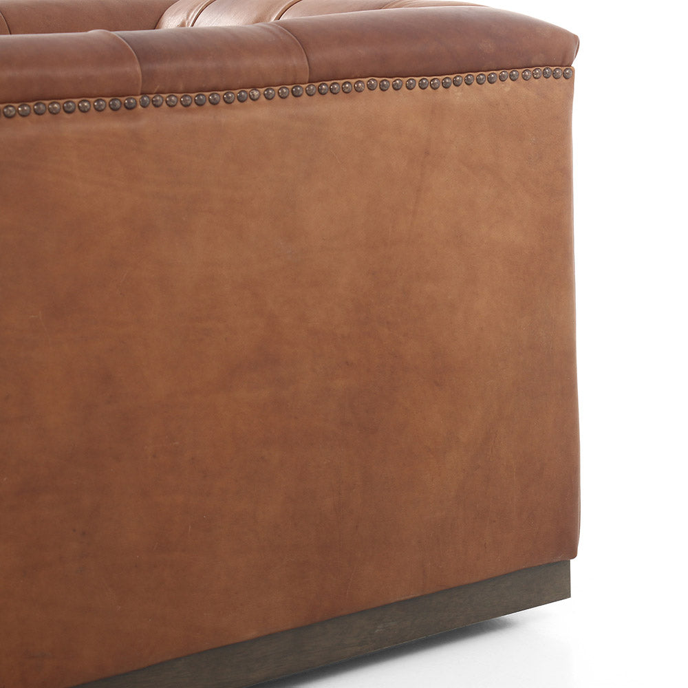Close up of side view on Four hands brand Maxx squared arm Chesterfield style swivel chair in brown leather with nail heads on a white background