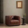 Four hands brand Maxx squared arm Chesterfield style swivel chair in brown leather with nail heads in a room with grey paint and a dark side table