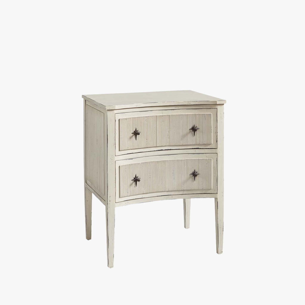 Aged white side table with two drawers and star shaped pulls on a white background