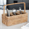 Rectangular rattan caddy with handle and three compartments on a kitchen counter with silverware