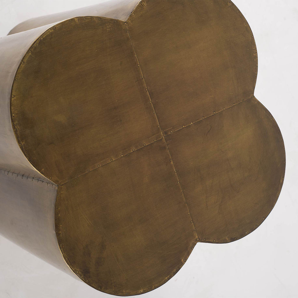 Close up of top of table with brass cladding on clover shaped side table on a white background 