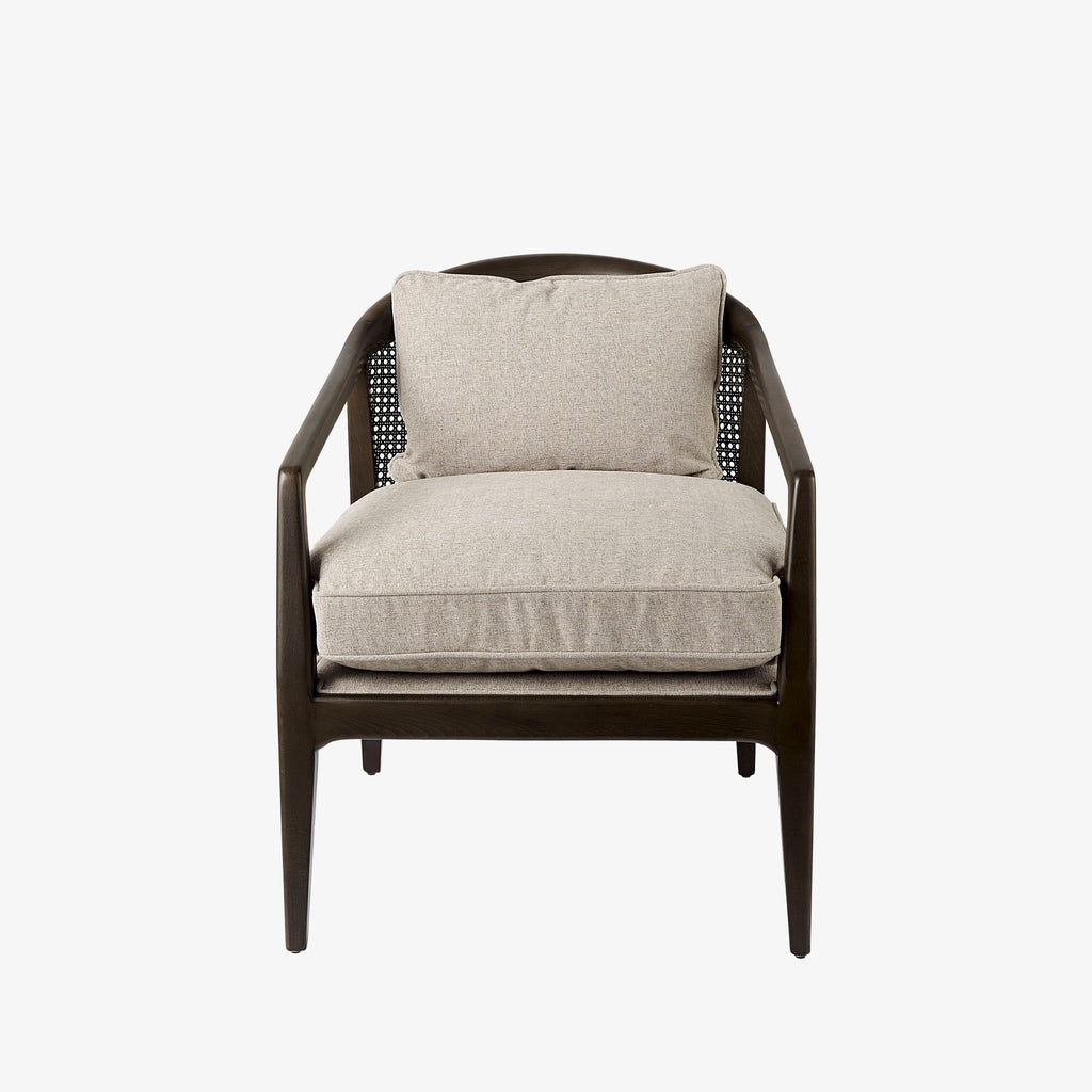 Armchair with dark brown stain and sloped arms and cane back and light beige cushions on a white background