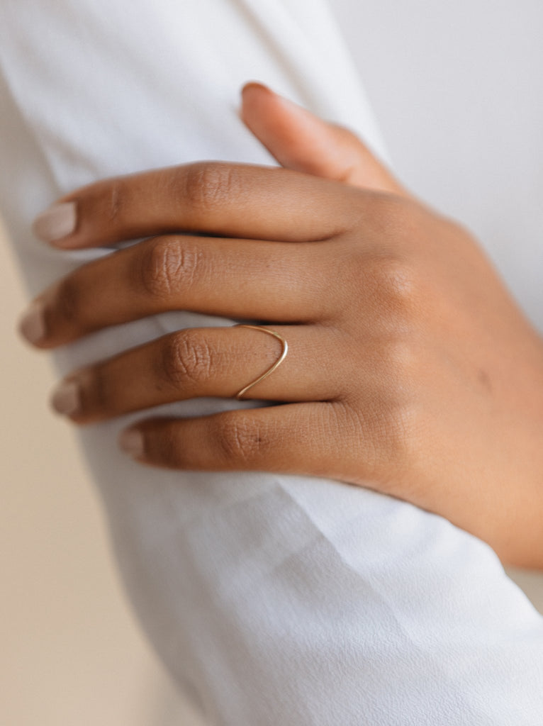 Model wearing Able brand Double V one size fits all ring in 14 carat gold fill on a white background