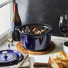 Blue staub tall cocotte dutch oven with mussels on a  table with red wine and bread
