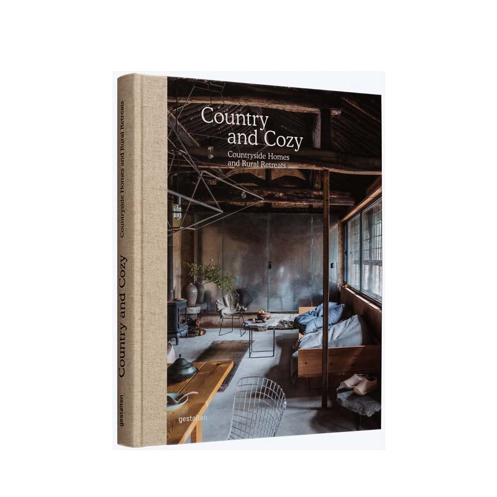 Front cover of book 'Country and Cozy: Countryside homes and rural retreats' showing wood beamed house interior on a white background