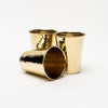 Three metal drinking cups with hammered brass finish on a white background