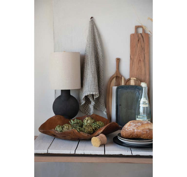 Black terracotta table lamp on a table with cutting boards and kitchen items