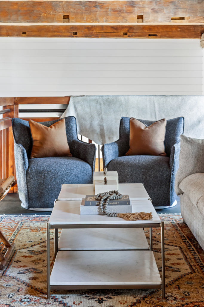 Rustic living area with two charcoal grey 'Kimble' swivel armchairs and wood beams and patterned wood rug