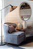 Blue swivel chair with nailheads next to wood table and floor lamp with pleated shade
