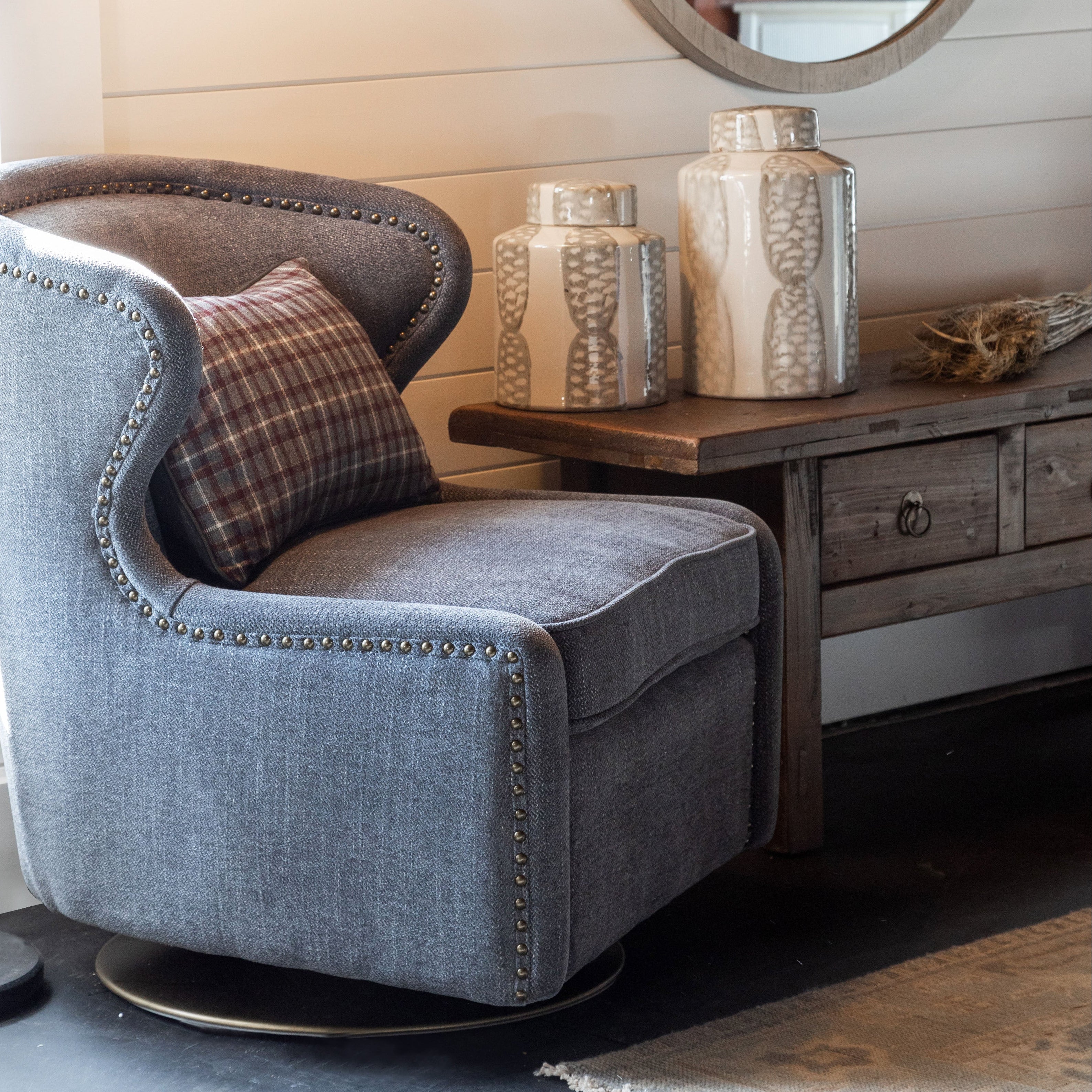 Room with lamp and blue swivel chair with mirror on wall and wood coffee table against white wall 