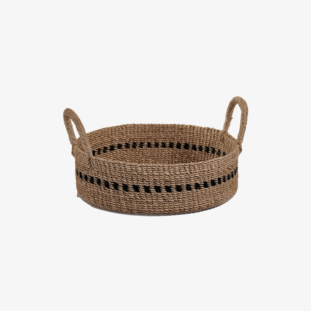 Low round woven basket with black accent and handles on a white background
