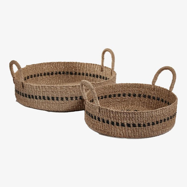 Two low round woven baskets with black accent and handles on a white background