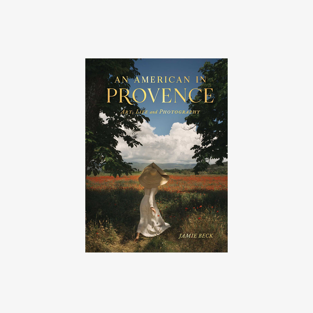 woman wearing dress and large hat in meadow of poppies on front cover of book titled 'An American in Provence: Art, Life and Photography'