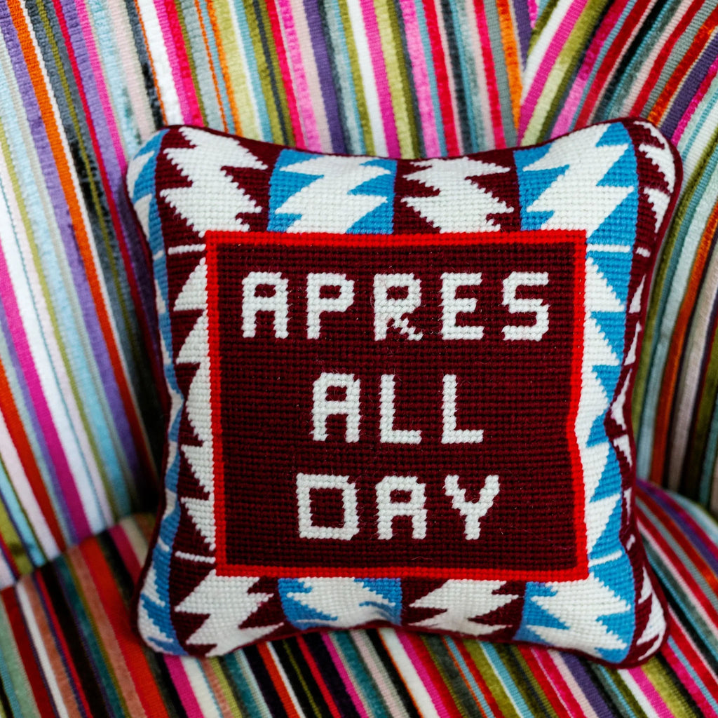 Needlepoint pillow with saying après all day  on a colorful striped chair
