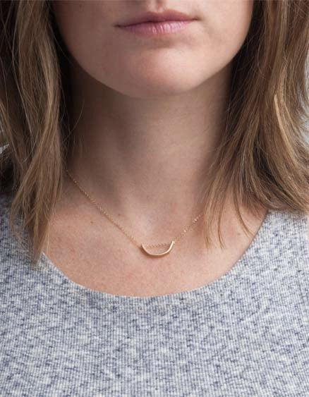 Brunette model wearing Able brand 14k gold filled arch necklace