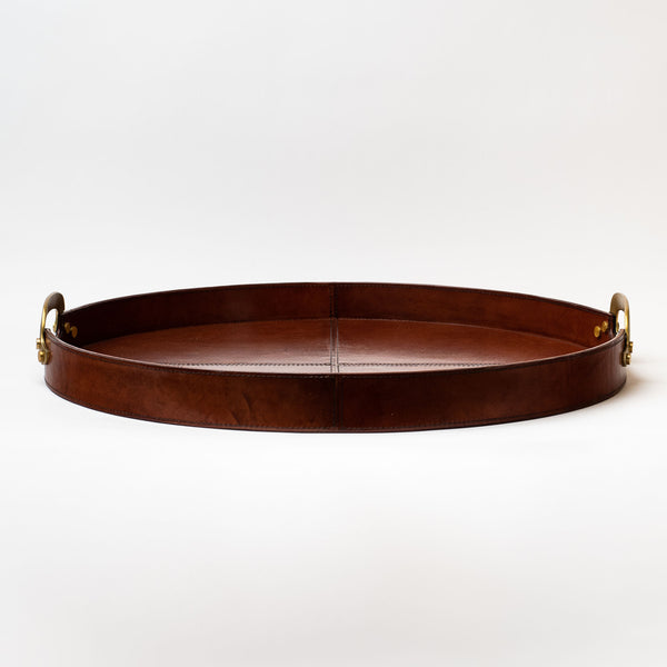 Large round leather tray with brass handles on a white background