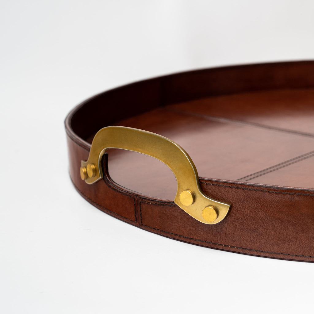 Close up of Large round leather tray with brass handles on a white background