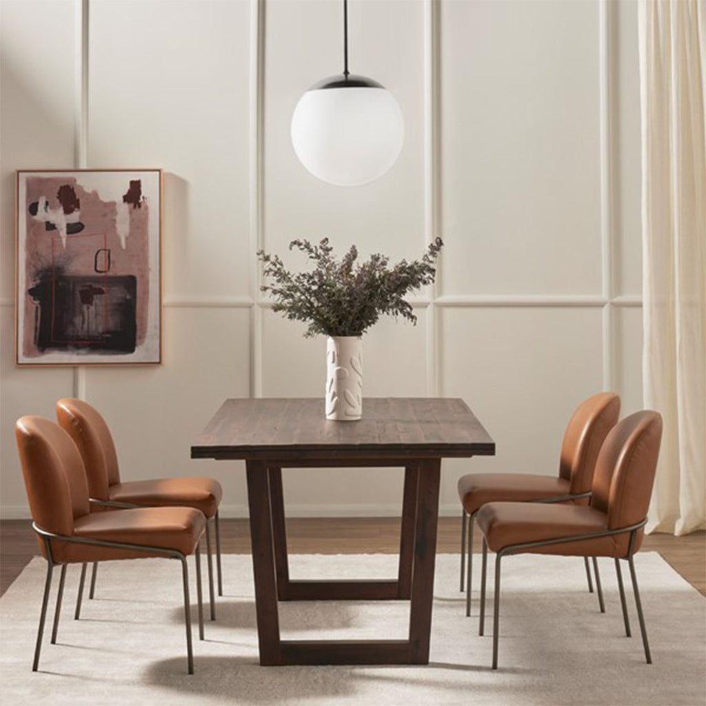 Dining room with wood table and cream rug and mid century pendant with Four Hands Brand Astrud dining chair with brown leather seat and back and iron legs around table