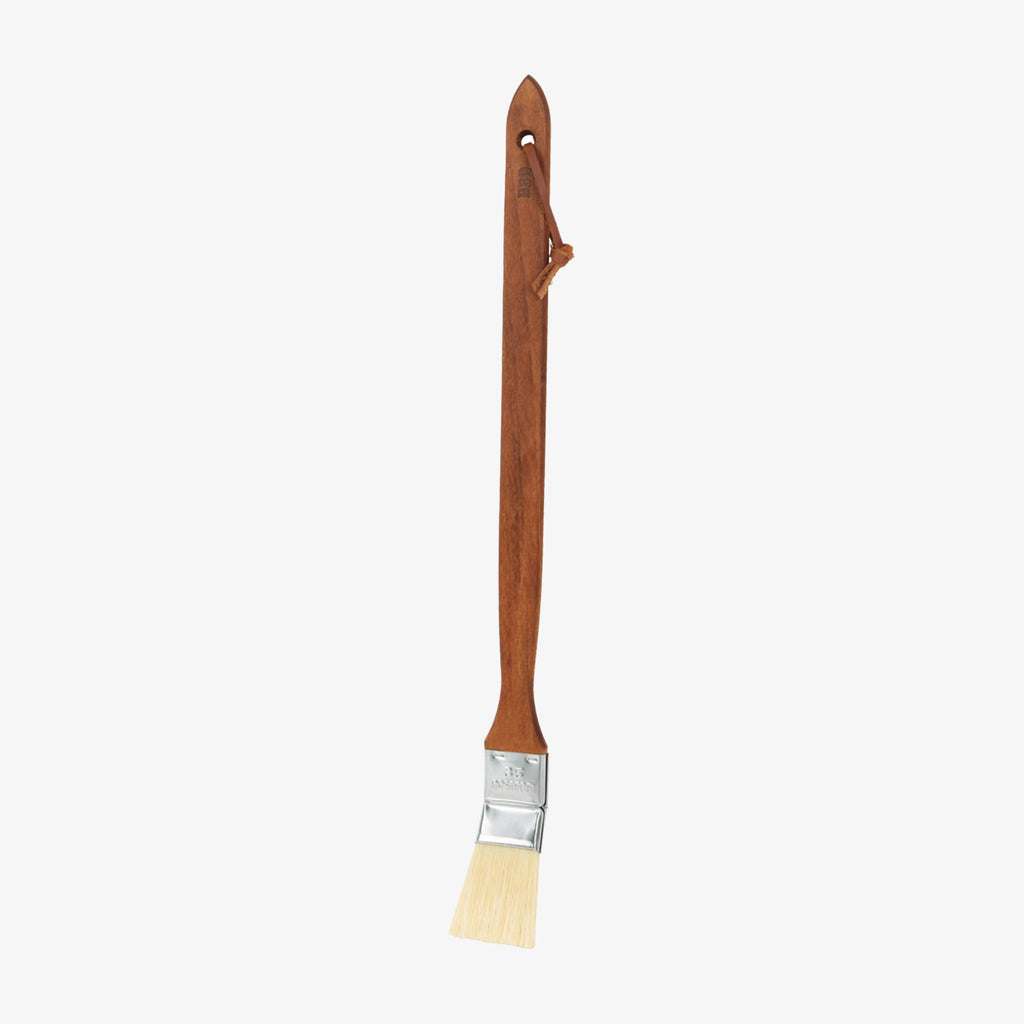 Long wood handled barbecue brush on a white background