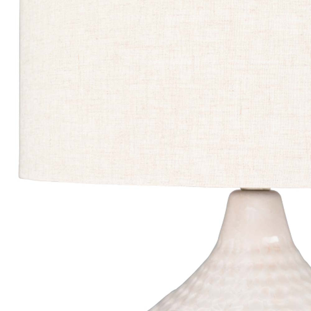 Close up of Surya Blakey table lamp with round white base and linen shade on a white background