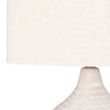 Close up of Surya Blakey table lamp with round white base and linen shade on a white background