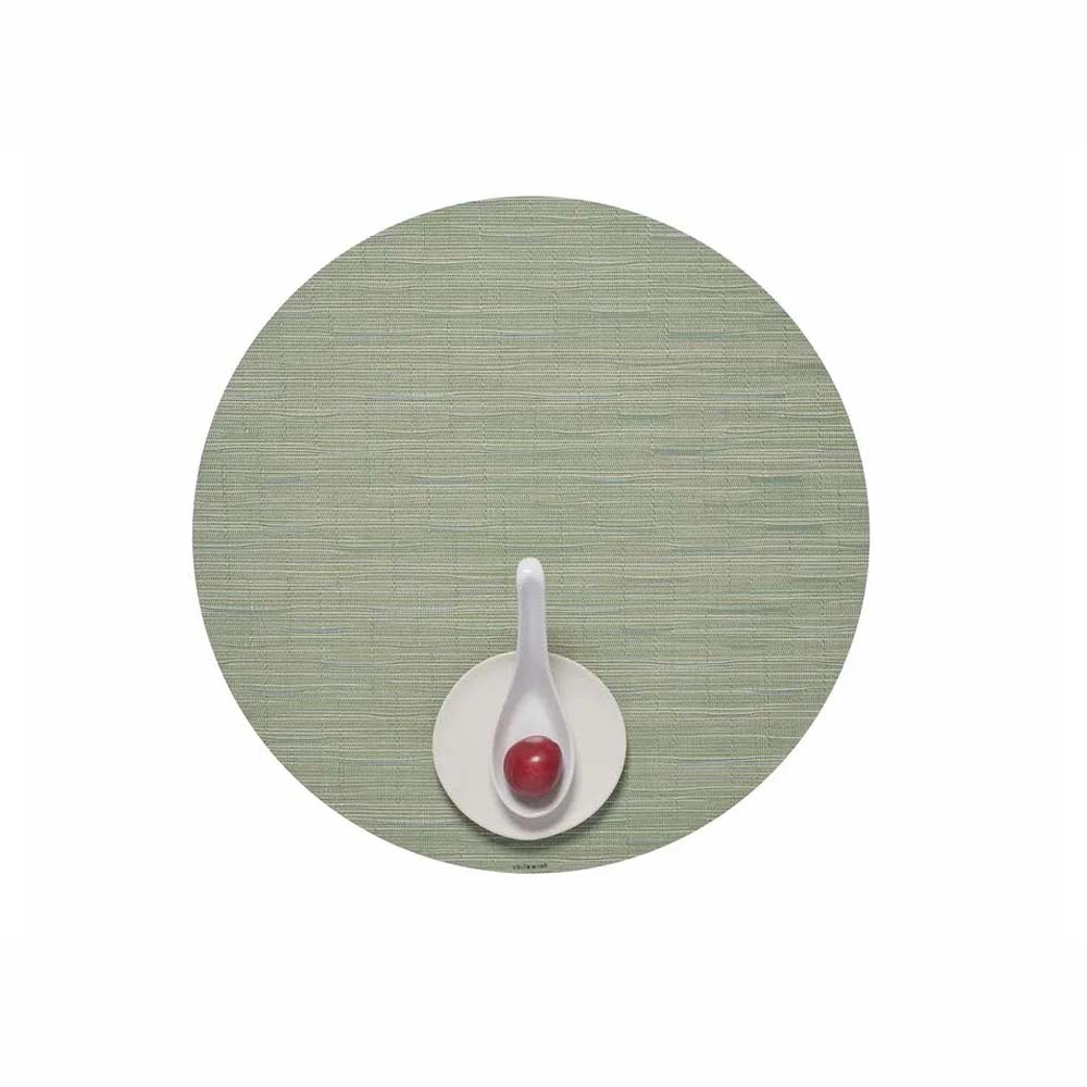 Chilewich Bamboo Signature round placemat in spring green color on a white background with a small plate and white spoon