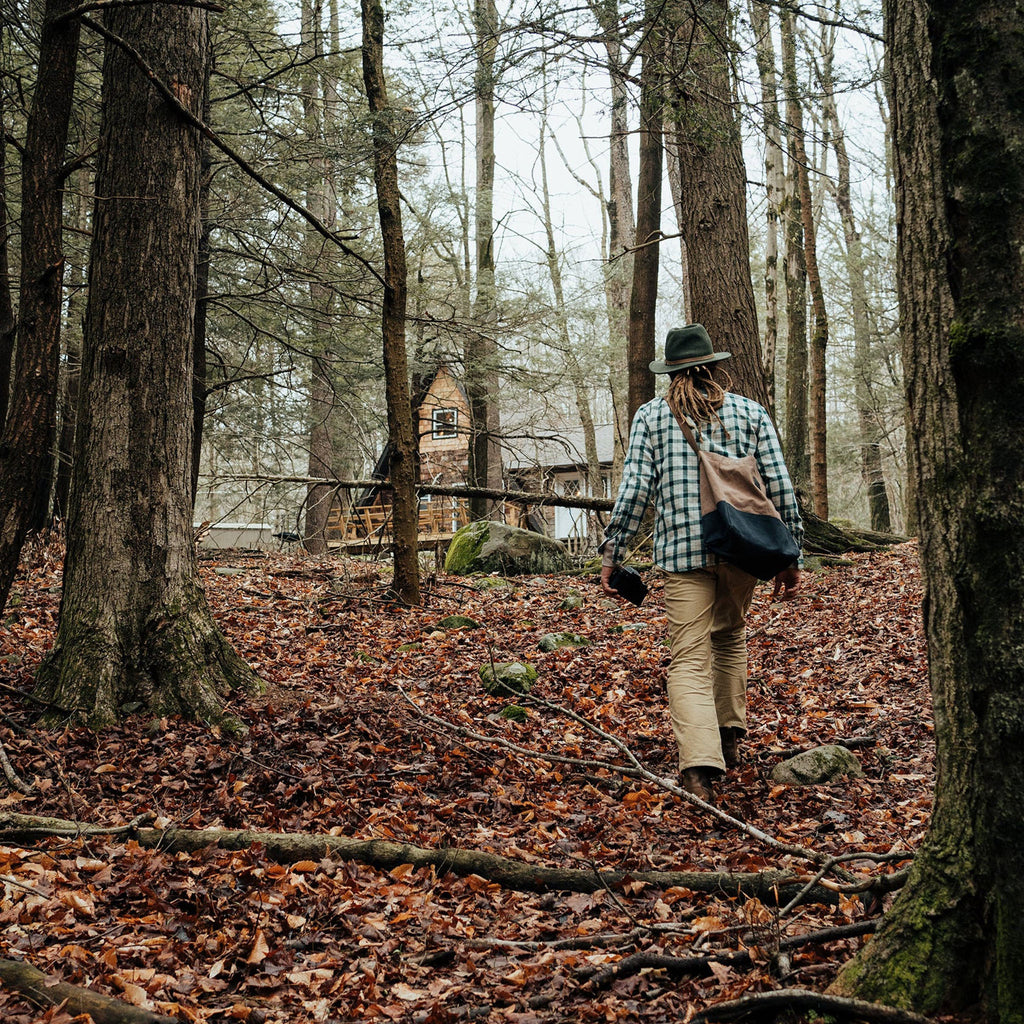 Woman in the woods with khakis and a hat on carrying the barebones brand neelum tote bag