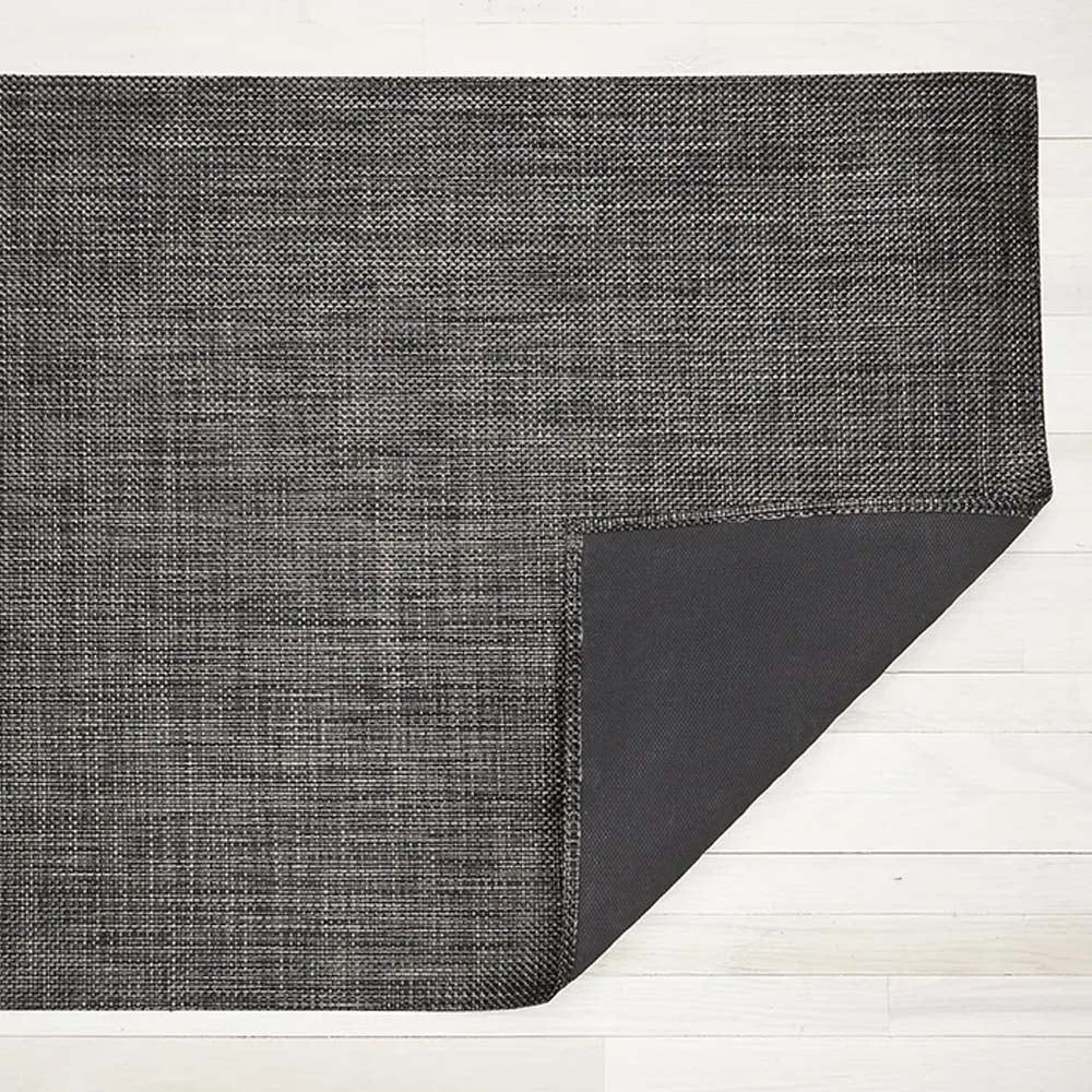 Chilewich basketweave woven floor mat in carbon on a light wood floor
