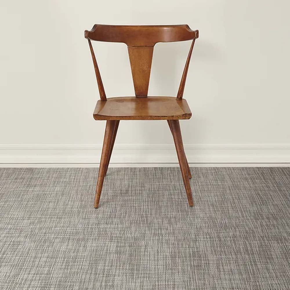 Chilewich basketweave floor mat in oyster on a light wood floor with brown wood chair
