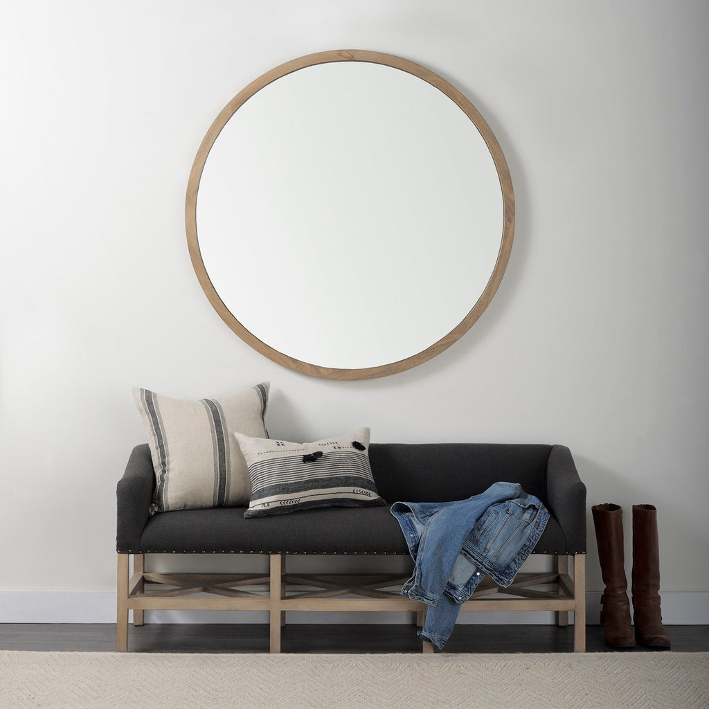 Grey upholstered accent bench with trellis wood base and small bolster back and nail head finish in entry way with mirror hanging above