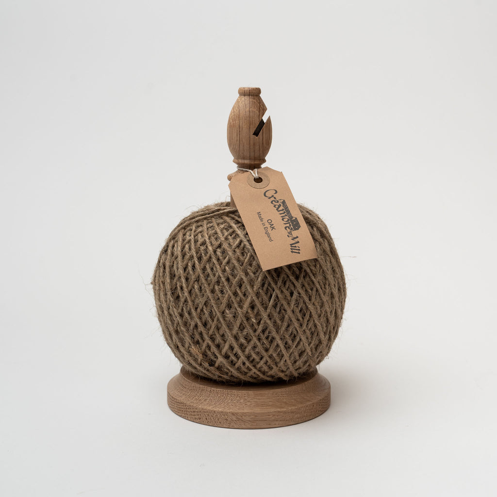Oak twine stand with built in cutter and ball of jute twine on a white background