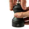Close up of Peugeot Paris bistro graphite pepper mill on a white background with hands