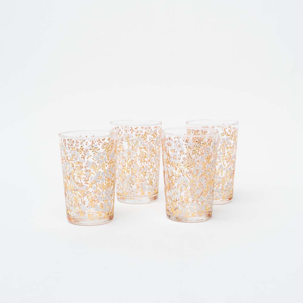 Set of four tea glasses with white and gold blossom design on a white background
