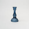 Blue pressed glass candlestick on a white background