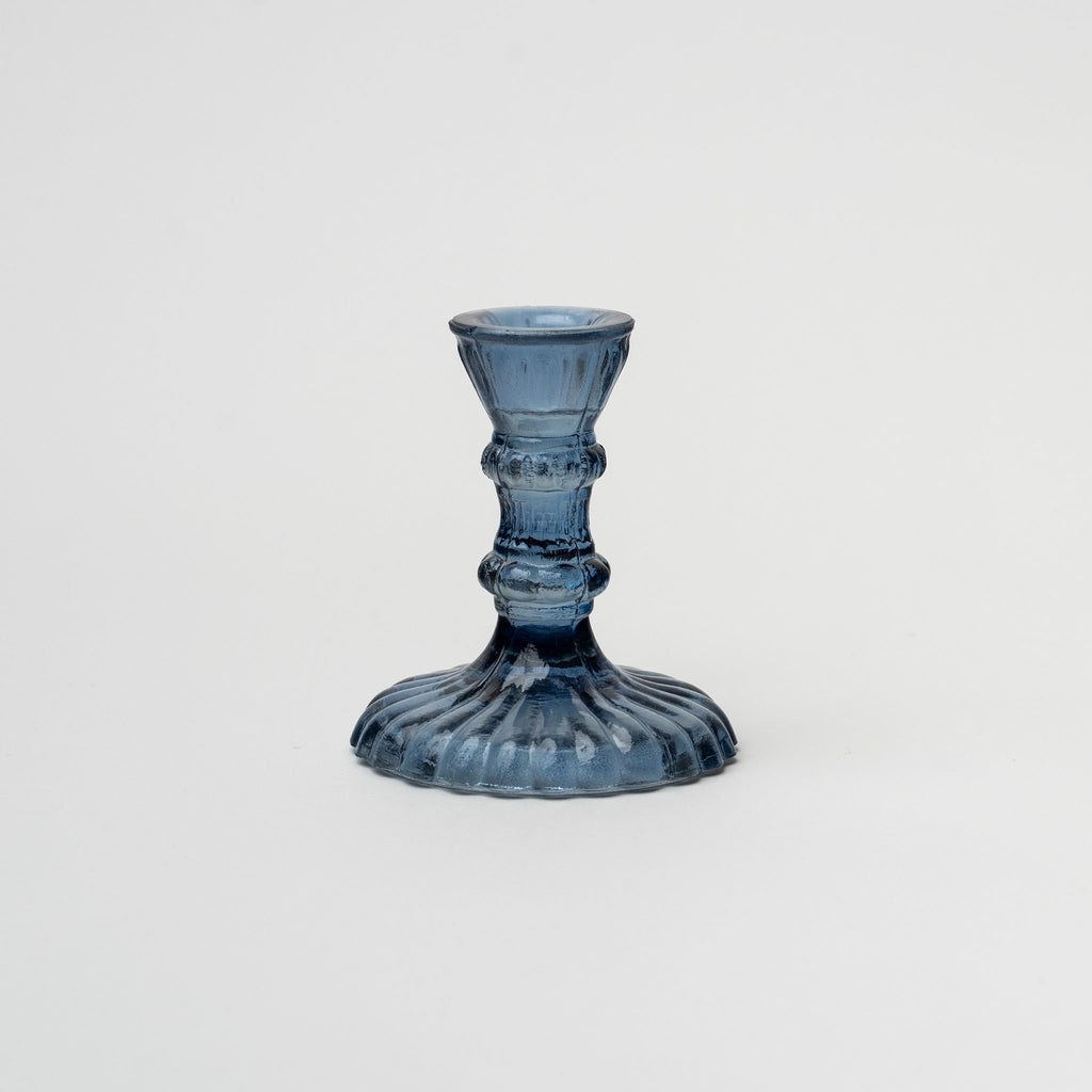 Blue pressed glass candlestick on a white background