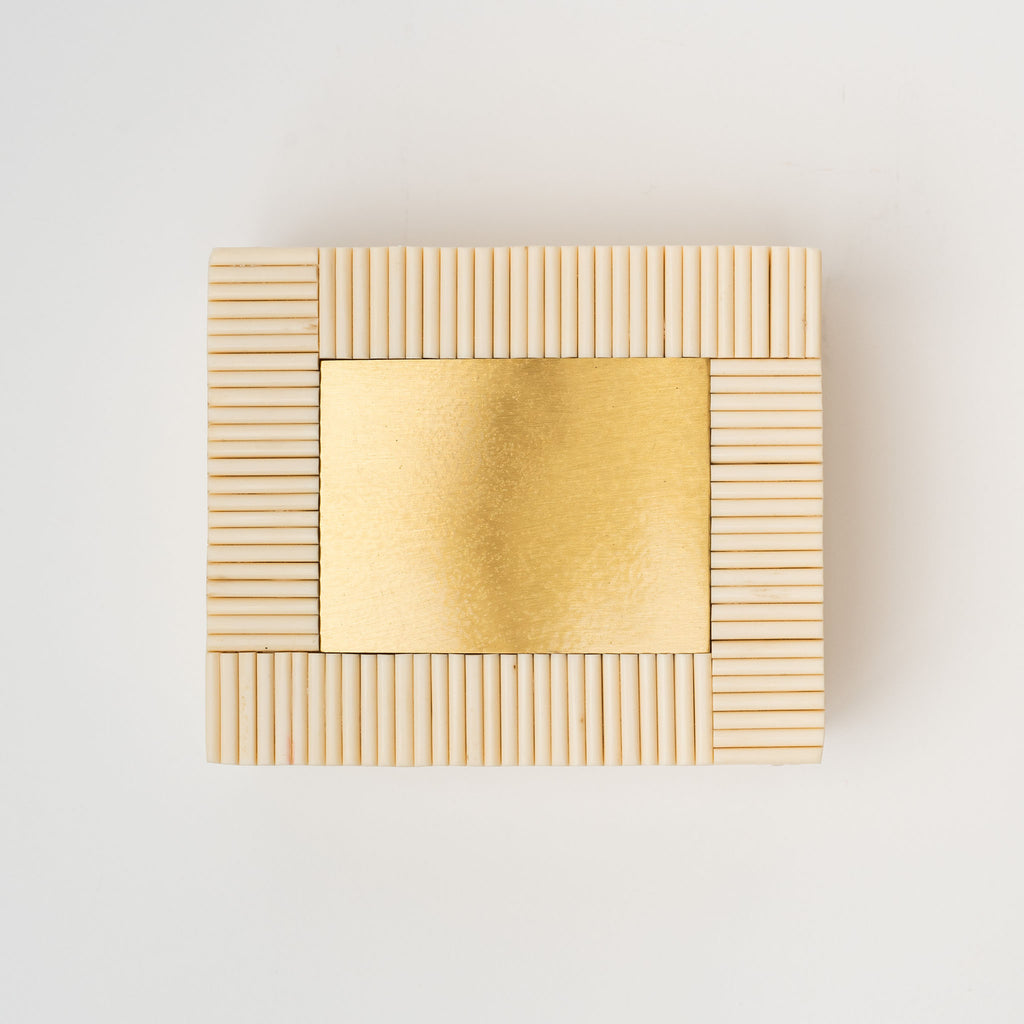 White rectangular box made of bone Redding with brass inset on a white background