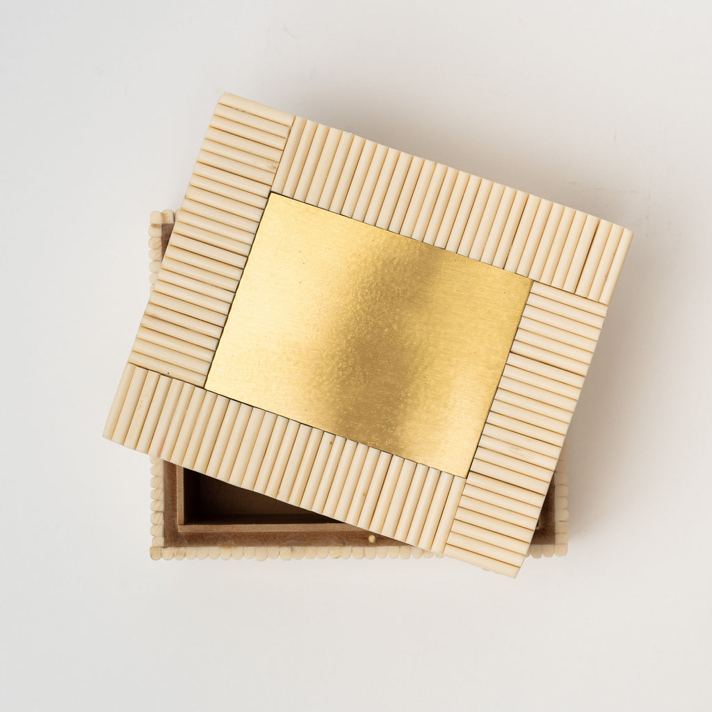 White rectangular box made of bone Redding with brass inset on a white background