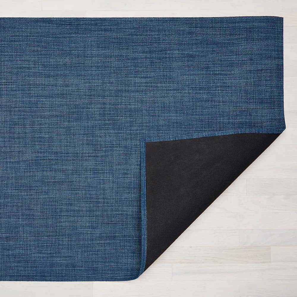 Chilewich boucle blue floor mat in blueberry color on a light wood floor